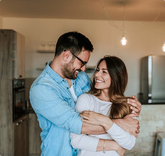 Casal abraçado na cozinha da casa nova